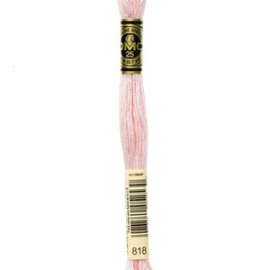May include: A spool of DMC embroidery floss in colour 818, a light pink shade. The spool is labelled with the DMC logo and the number 25, indicating the length of the floss is 8.7 yards.