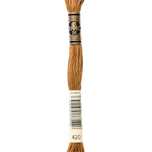 May include: A spool of DMC embroidery floss in colour 420, a brown shade. The spool is labelled with the DMC logo and the number 25, indicating the length of the floss is 8.7 yards.