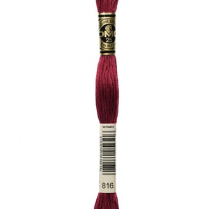May include: A spool of DMC embroidery floss in colour 816, a deep burgundy red. The floss is wound around a white cardboard spool with a gold label that reads "DMC 25 8 m (8.7 yds)".