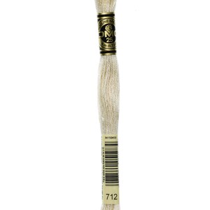 May include: A spool of DMC embroidery floss in colour 712, a light cream shade. The spool is labelled with the DMC logo and the number 25, indicating the length of the floss is 8.7 yards.