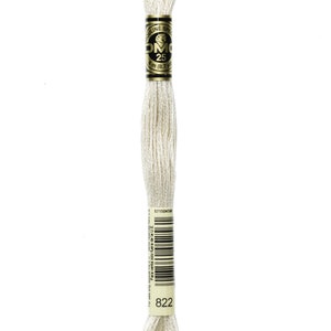 May include: A spool of white DMC embroidery floss with a gold label that reads "Mouline Special DMC 25 8m (8.7 yds)" and a barcode. The spool number is 822.