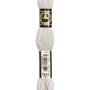 May include: A skein of DMC Tapestry Wool in colour 7510, a light off-white shade. The skein is wrapped in black and gold packaging featuring the DMC logo and the words "Laine Colbert" and "Tapestry Wool". The packaging also includes the lot number, colour number, and the DMC logo.