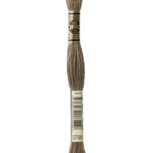 May include: A spool of DMC embroidery floss in colour 3790, a light brown shade. The spool is labelled with the DMC logo and the number 25, indicating the length of the floss. The label also includes the text "Mouline Special" and the length of the floss in metres and yards.