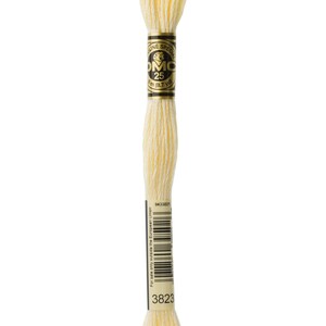 May include: A skein of DMC embroidery floss in colour 3823, a pale yellow. The floss is wound around a cardboard spool with a gold label that reads "DMC Special 25 8.7 yd".