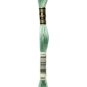 May include: A skein of DMC embroidery floss in colour 966, a light green shade. The floss is wound around a white card with black text that reads "DMC" and "966".