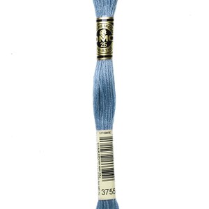 May include: A skein of DMC embroidery floss in a light blue colour. The floss is wound around a cardboard spool with a gold label that reads "DMC" and "25". The label also includes the text "Spec. Line" and "3 m (8.7 yd)".