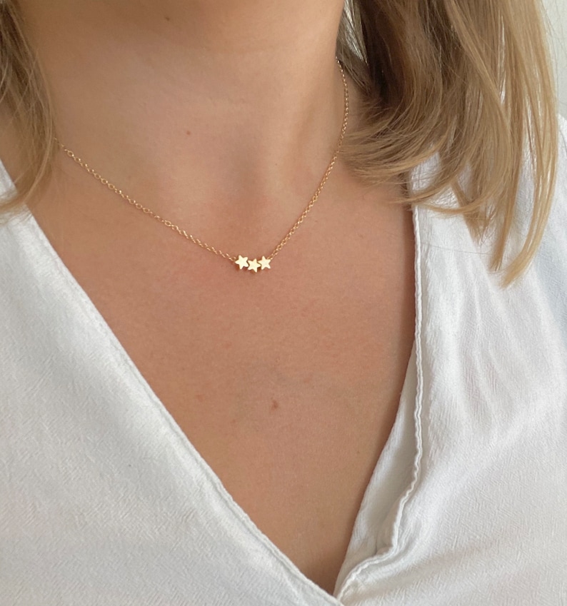 May include: A gold chain necklace with three small star charms.