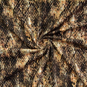 Könnte beinhalten: Ein Stoff mit einem sich wiederholenden Schlangenhautmuster in Schwarz-, Beige- und Hellbrauntönen. Das Material ist in der Mitte gerafft, wodurch Falten und Drapierungen entstehen, die die komplexe, rautenförmige Schuppenstruktur auf der Oberfläche betonen.
