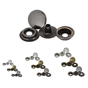 Könnte beinhalten: Sortiment an Metall-Druckknöpfen in verschiedenen Ausführungen, darunter Silber, Gold und Schwarz. Die Druckknöpfe befinden sich in verschiedenen Montagephasen und zeigen Kappe, Stift und Buchse.