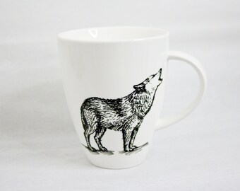 May include: White ceramic mug featuring a black illustration of a howling wolf. The mug has a curved handle and a simple, elegant design. Ideal for coffee, tea, or any favorite beverage.