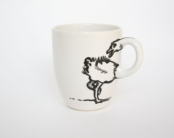May include: White ceramic mug with a whimsical black illustration of a bird. The bird's body is on the mug, and its head forms the handle. A unique and artistic design for coffee or tea.