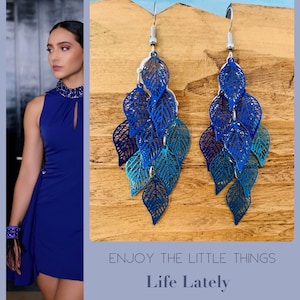 Könnte beinhalten: Ein Paar blaue und silberne Ohrringe mit einem Blattdesign. Die Ohrringe sind aus Metall und haben einen zarten, femininen Look. Der Text "Enjoy the little things Life Lately" ist am unteren Rand des Bildes sichtbar.