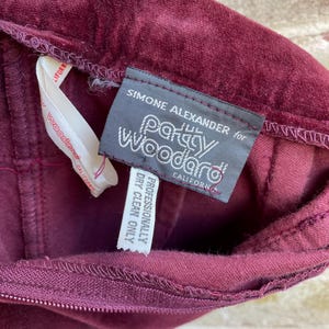 May include: A burgundy velvet skirt with a label that reads "Simone Alexander for Party Woodard, California. Professionally Dry Clean Only."