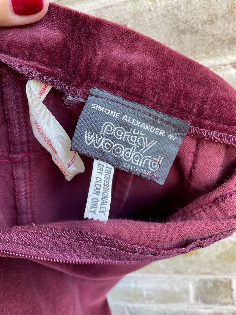 May include: A burgundy velvet skirt with a label that reads "Simone Alexander for Party Woodard, California. Professionally Dry Clean Only."
