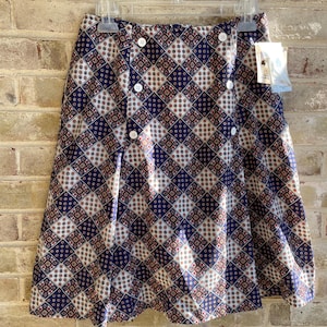May include: A blue and white patterned skirt with a button closure. The skirt has a diamond pattern with small floral details.