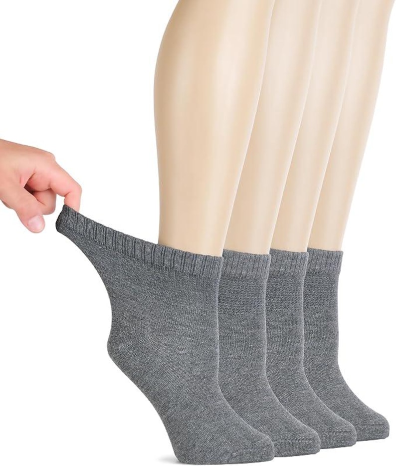 May include: A set of four grey ankle socks featuring a ribbed cuff at the top. The socks are made of a knit fabric with a heathered texture. Each sock has a reinforced heel and toe area, providing a consistent look across all four pieces.
