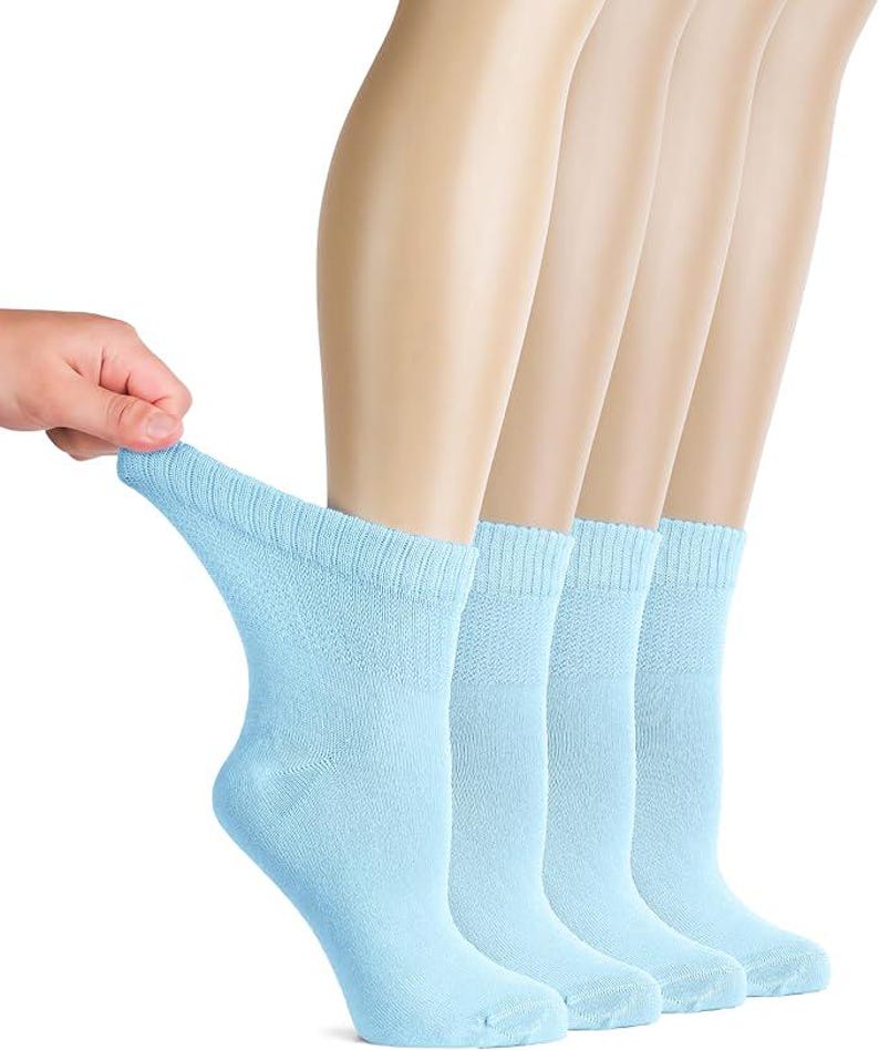 May include: A set of four light blue ankle socks featuring a ribbed cuff design. The socks are made of a soft, knit fabric and are shown in a light, solid color. The material has a consistent texture throughout the body of the sock, providing a simple and functional appearance for everyday use.