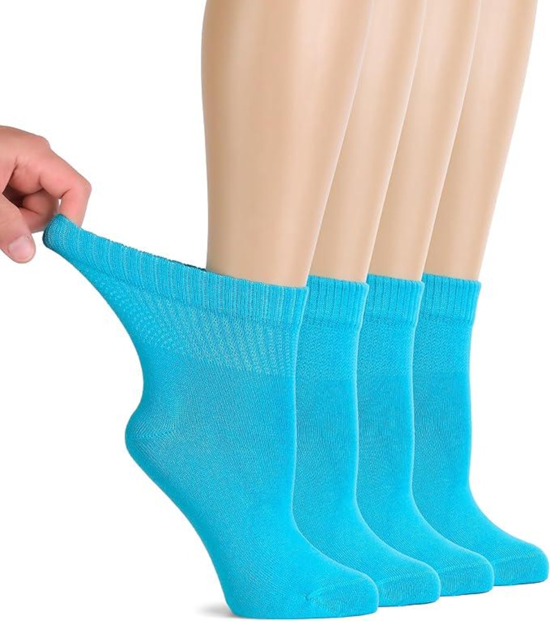 May include: A set of four bright turquoise ankle socks featuring a ribbed cuff design. The fabric is shown being stretched to demonstrate elasticity, highlighting the solid color and the knit texture of the material throughout the garment.