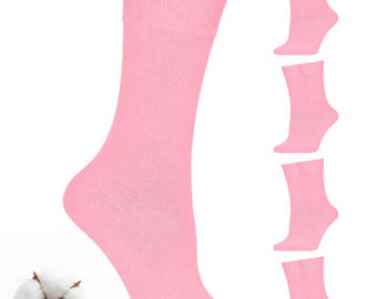 May include: A set of solid light pink crew socks featuring a ribbed cuff at the top. The socks are shown worn on a lower leg, with four additional pairs displayed vertically to the right and a single white cotton boll positioned on the left.