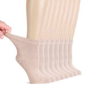 May include: A set of multiple beige ankle socks with a ribbed cuff design. The socks are displayed on a mannequin foot form, showing the texture and neutral color of the fabric. The material appears soft and opaque, covering the foot and ankle area.
