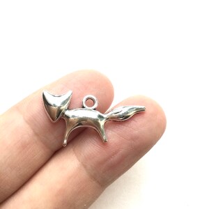 May include: Silver fox charm pendant with a simple, stylized design. The charm is perfect for adding a touch of whimsy to jewelry projects.