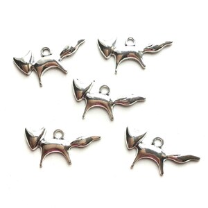 May include: Five silver fox charms with a simple, stylized design. Each charm has a loop for attaching to a necklace, bracelet, or other jewelry.