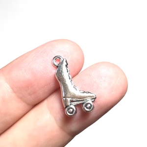 May include: Silver roller skate charm with a detailed design. The charm has a loop at the top for attaching to a necklace or bracelet.