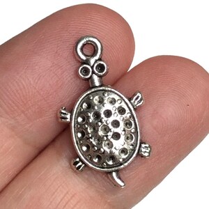 May include: Silver turtle charm with a textured shell and a loop for attaching to a necklace or bracelet.