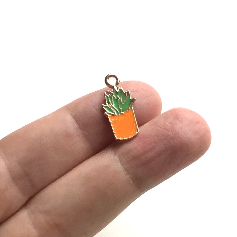 Pode incluir: Charme dourado com um design de abacaxi verde. O abacaxi &eacute; laranja e tem um la&ccedil;o dourado para prender a um colar ou pulseira.