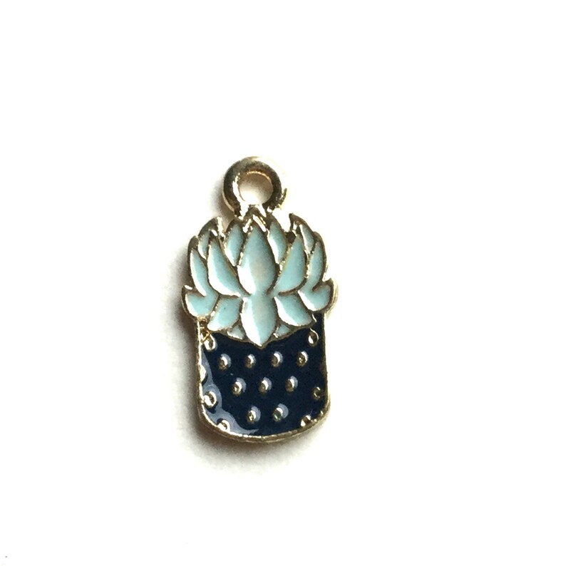 Pode incluir: Encanto de ouro com um design de planta suculenta de esmalte azul e branco. A suculenta est&aacute; em um vaso preto com bolinhas brancas.