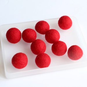 May include: A clear plastic container filled with ten red felt balls.