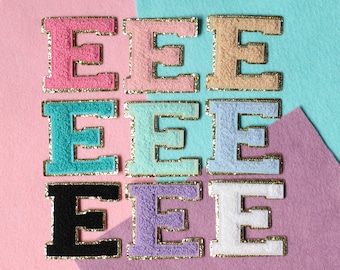 May include: Nine felt letter patches in various colors, each with a gold outline. The colors include pink, light blue, turquoise, lavender, white, and black. The letters are all the letter "E".