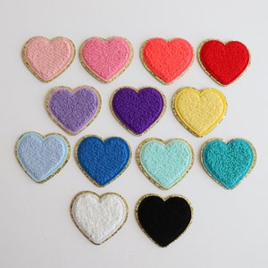 May include: Assortment of 14 felt heart patches in various colors, including pink, red, blue, purple, yellow, turquoise, white, and black. Each heart is outlined with a gold trim.