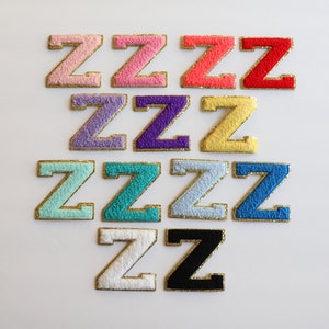 May include: A set of 10 felt letter patches in various colors, each featuring the letter "Z" in a gold outline. The colors include pink, red, purple, yellow, light blue, turquoise, white, and black.