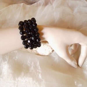 Könnte beinhalten: Ein schwarzes Armband mit mehreren Reihen facettierter Perlen. Das Armband wird am Handgelenk einer Schaufensterpuppe getragen.