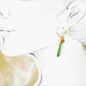 K&ouml;nnte beinhalten: Ein Paar goldene Ohrringe mit gr&uuml;nen und wei&szlig;en Edelsteintropfen.