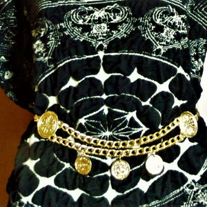 May include: A black and white patterned blouse with a gold chain belt featuring round medallions.