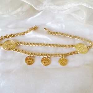 May include: A gold chain belt with five round, decorative, gold medallions.