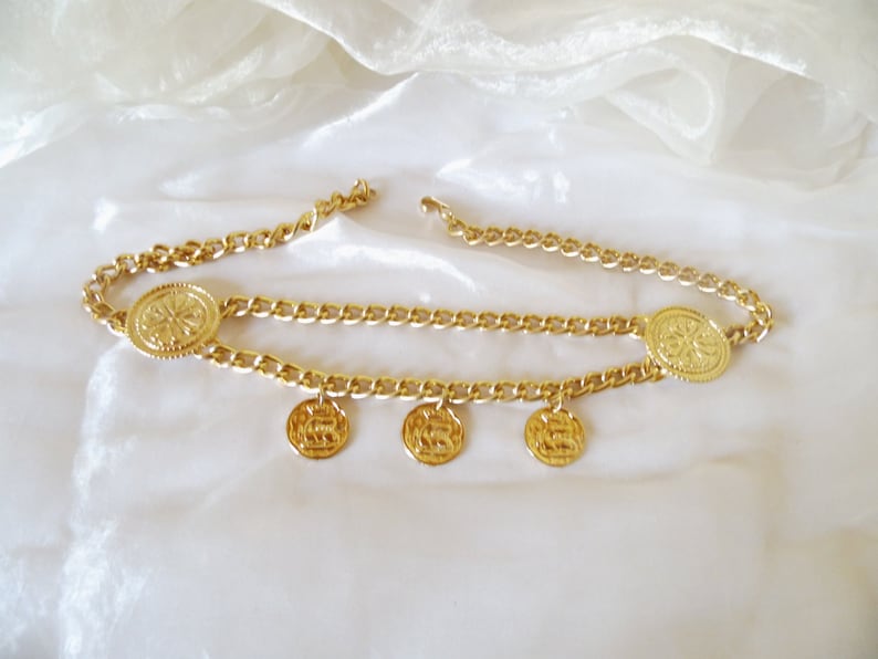 May include: A gold chain belt with five round, decorative, gold medallions.