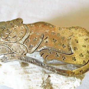 Könnte beinhalten: Ein silberfarbener Metall-Lesezeichen in Form einer zusammengerollten Katze mit einem Blumenmuster.