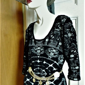 May include: A black and white patterned dress with a gold chain belt and a straw hat with a black ribbon.
