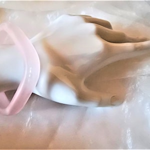 Könnte beinhalten: Ein quadratisches Armband aus hellrosa Plastik.