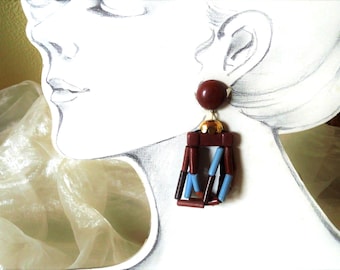 May include: A pair of dangle earrings with brown and blue beads. The earrings are made of wood and have a gold-tone metal accent.