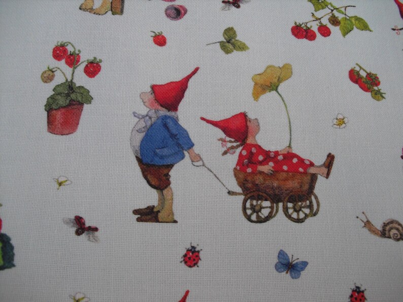 May include: White fabric with a whimsical print featuring gnomes, strawberries, flowers, butterflies, and a snail. One gnome pulls a cart with another gnome inside. The gnomes wear red hats and are surrounded by nature elements.