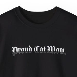 May include: Black t-shirt with the text "Proud Cat Mom." in white gothic lettering.