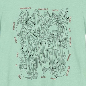 May include: A green t-shirt with a black and white graphic design of geometric shapes. The text "WARNING: HANDLE WITH CARE MY FRIEND! SHARP OBJECTS YOU MAY CUT IF YOU LOSE FOCUS." is printed in red around the graphic.
