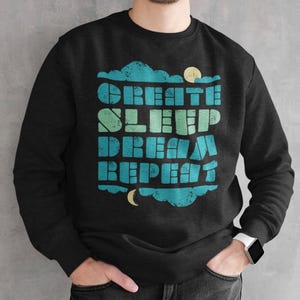 May include: Black sweatshirt with a blue and green graphic print that says "Create Sleep Dream Repeat" with a moon and clouds.