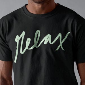 May include: A black t-shirt with a light green cursive inscription that reads "Relax".