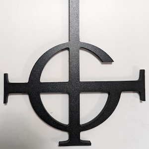 May include: Black metal cutout of the Ghost band symbol, a circle with a cross inside, and a vertical line extending from the top of the circle.