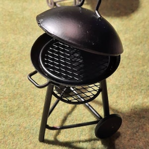 May include: A black metal grill with a lid and a wire rack. The grill is on a tripod stand with wheels.